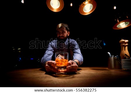 The bartender at  bar with a glass of alcohol in his hands
