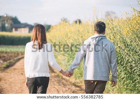 Young couple are happy and standing on a meadow in the morning on winter season. Green and yellow grass on background.