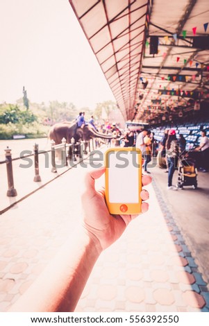 hand holding the phone tablet at outdoor and restaurant background. Transactions by smartphone concept. To represent action as texting message, chat with other and snap the picture via smart phone. 