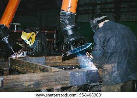 Worker at the factory in the helmet is of iron in the welding process bright sparks