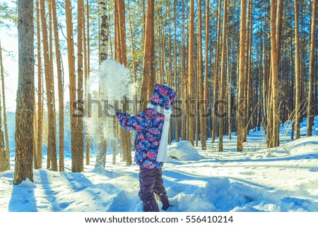 Girl throws snow in sunny winter forest 