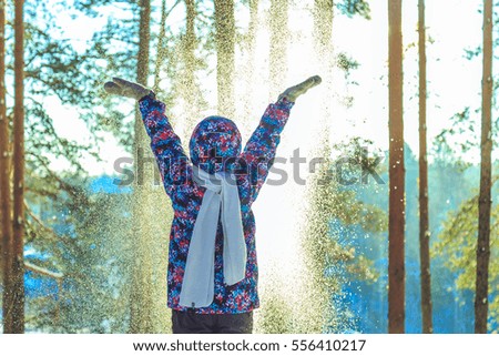 Girl throws snow in sunny winter forest 