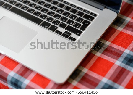 Laptop Computer on the Home Table Covered with Traditional Red Checkered Tablecloth. Top View with Space for Text