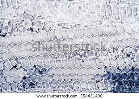 Trace of car tires in the snow. Close up view from above, image in the blue toning