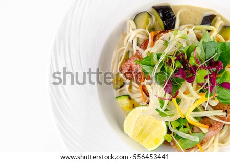 Fillet of sea bass with roasted eggplant and olives on a plate on a white background, top view closeup