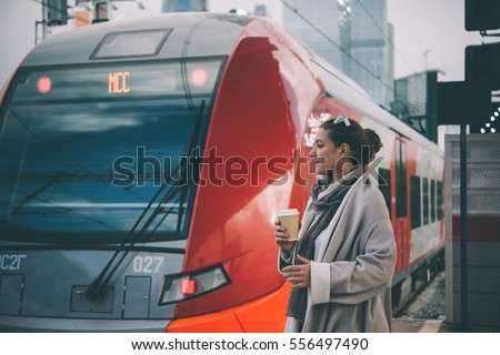 Young beautiful woman enjoys her coffee at the platform as Moscow Central Circle train arrives. Toned picture