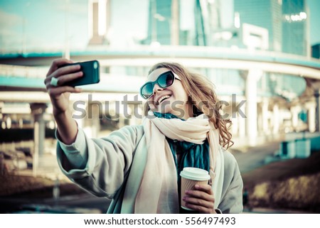 Young beautiful woman takes a selfie with Moscow City international business center in the background. Toned picture