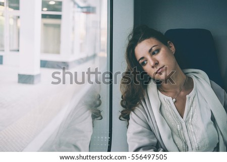 Young sad woman looking through the train window. Toned picture