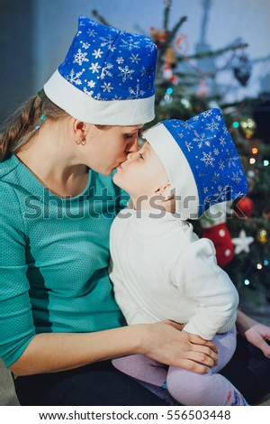 Mother kisses the child against the background of the Christmas tree