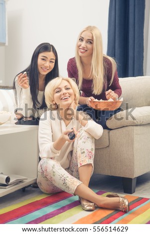 Toned picture of friends girls having party all together at home. Beautiful women watching films or movies and eating pop corn. Happy ladies smiling for camera.