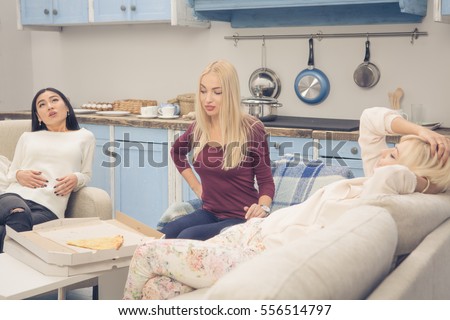 Home party concept. Toned picture of beautiful ladies ready to sleep after rest or relax. Friends girls resting after eating delicious pizza while having party at home.