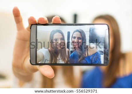 Friends taking self portrait with smart phone at home.