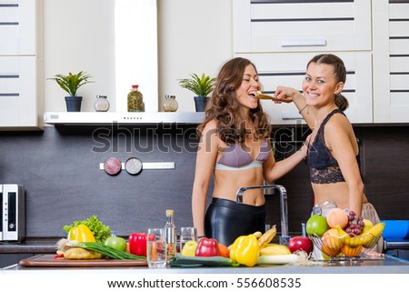 Two twin sisters having fun in the morning preparing breakfast in the kitchen