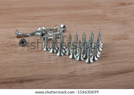 Pile of metallic screws in triangle shape lay on wooden table