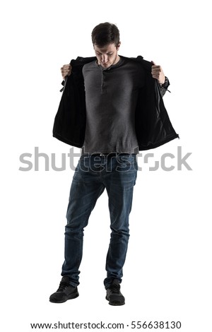 Silhouette back lit casual man taking off jacket looking down. Full body length portrait isolated over white background.