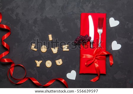 Valentines day table setting with fork, knife and cookies I LOVE YOU on black background, Top view
