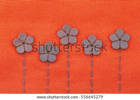 Leather flowers on embroidery pattern on orange canvas