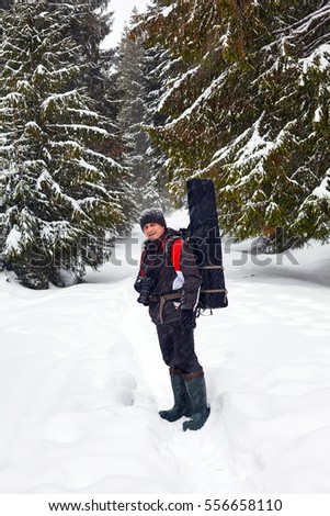 Professional landscape photographer walking through fir forest on wintertime