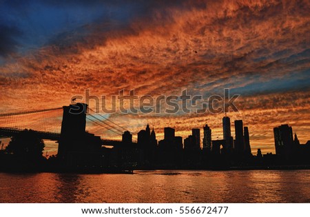 Silhouette of Manhattan skyline with Brooklyn Bridge at sunset - HDR image.