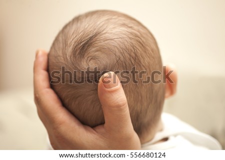 Closeup of baby head in father's hand.