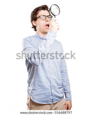 Surprised young man using a magnifying glass