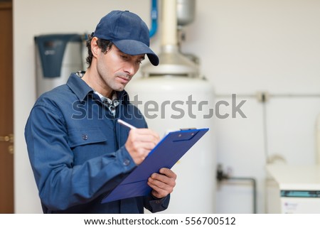 Technician servicing an hot-water heater Royalty-Free Stock Photo #556700512