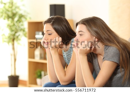 Bored roommates or friends sitting on a sofa in the living room at home Royalty-Free Stock Photo #556711972