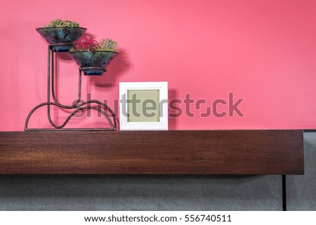 Flower vase of Bromeliad plants & photo frame on wooden shelf / lifestlye & modern home interior decoration conceptual