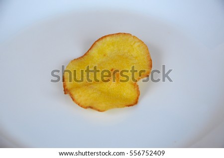 Dried and fried cassava slices place on white plate isolated on wood texture background. This is local Malaysian traditional junk food call Kerepek Ubi.   
