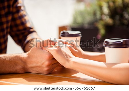 Close up of young couple holding each other hands in cafe Royalty-Free Stock Photo #556761667