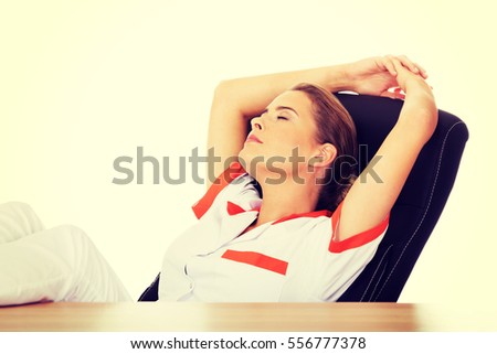 Young tired female doctor sleeping with legs on the desk