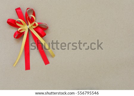 red and gold satin bow ribbon at the corner on brown paper background