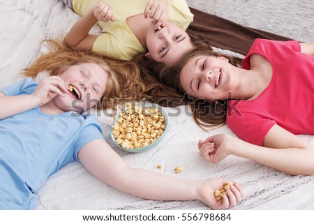 happy little girls  eating popcorn at home