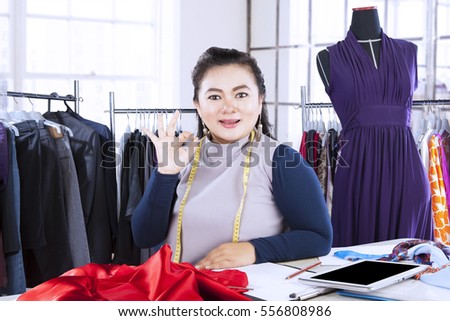 Portrait of professional designer showing ok gesture while smiling at the camera in her workplace 