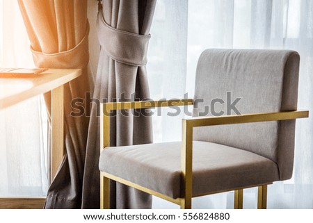 beige color upholstered chair in living room with curtain and soft lighting sunlight