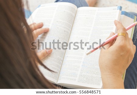 woman reading a book dictionary english for study Royalty-Free Stock Photo #556848571