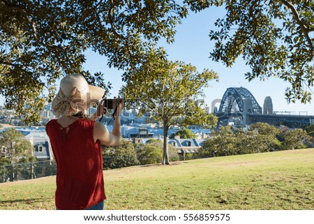 Woman in summer hat taking pictures of Sydney Harbour Bridge