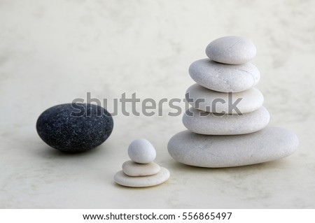 Harmony and balance, cairn, poise stones on light background, rock zen sculpture, five white pebbles, two towers, small, child, black stone