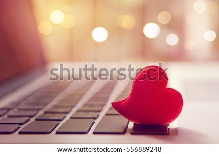 Red heart on the computer keyboard with sunlight and shadow. Internet dating, copyspace, Valentines day concept. Royalty-Free Stock Photo #556889248