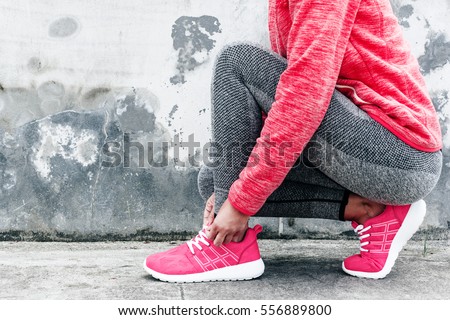Fitness sport woman in fashion sportswear doing yoga fitness exercise in the city street over gray concrete background. Outdoor sports clothing and shoes, urban style. Tie sneakers. Royalty-Free Stock Photo #556889800