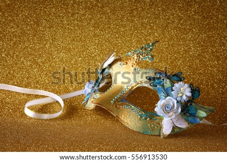 Image of elegant venetian mask on gold glitter background
