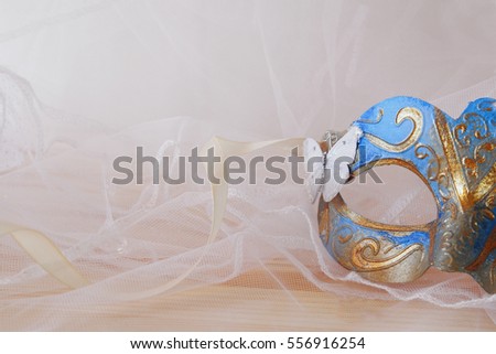 Image of delicate blue elegant venetian mask in front of white tulle background