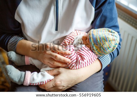 Happy proud young father holding his sleeping newborn baby daughter on arms in hospital. Dad with baby girl, love. New born child sleeping in dad's arms. Bonding, family, new life.