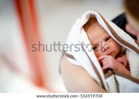 Mother holding her newborn baby daughter after birth on arms. Mum with baby girl, love. New born child cuddling in mama arms and looking at the camera. Bonding, family, new life Royalty-Free Stock Photo #556919704