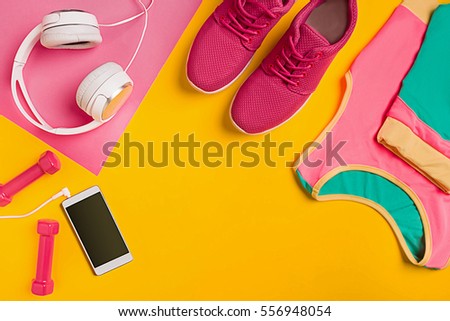 Athlete's set with female clothing, dumbbells and bottle of water on yellow background Royalty-Free Stock Photo #556948054