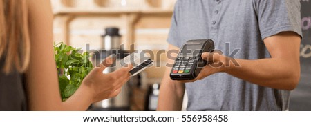 Woman paying with a debit card in a restaurant, waitress holding a payment terminal