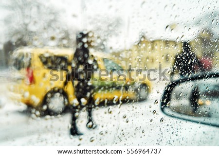 Blurred winter picture. Blurred background city street in winter in the snow from the car window. Taxi waiting passengers. Basic background for design

