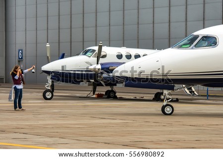 Young woman taking picture of bottle on the backgroung of business aircraft.