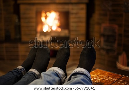 Close up of romantic legs in socks in front fireplace, stay home in quarantine