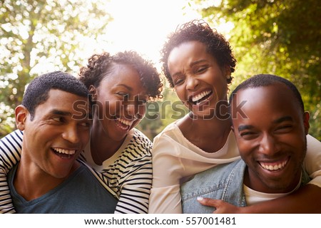 Two adult black couples have fun piggybacking, close up